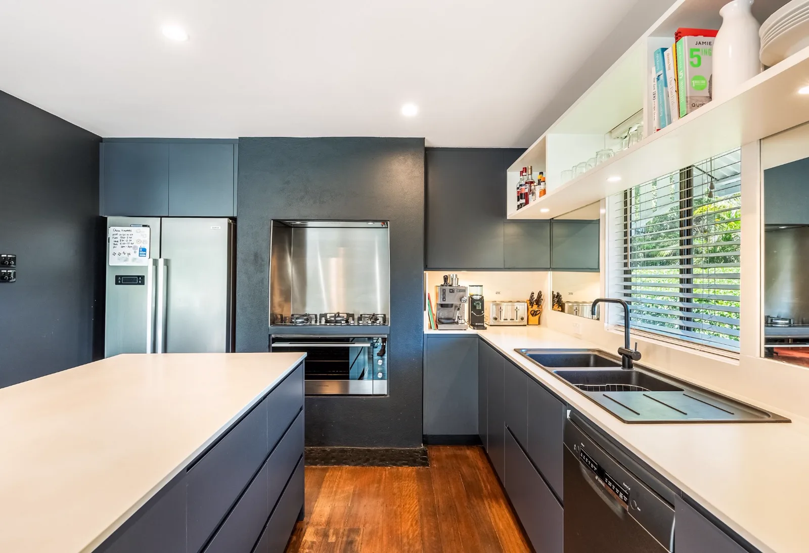 Galley kitchen with navy cabinetry, generated a second time in Hamptons with panelled walls, before
