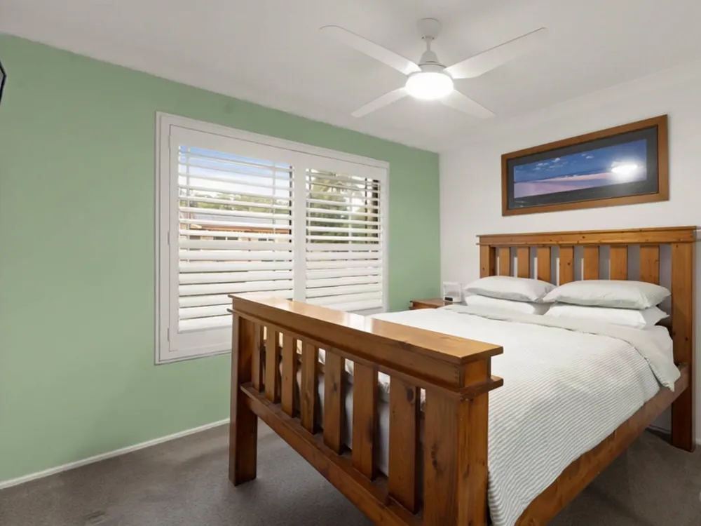 A bedroom with a single wall changed to sage green, everything else untouched